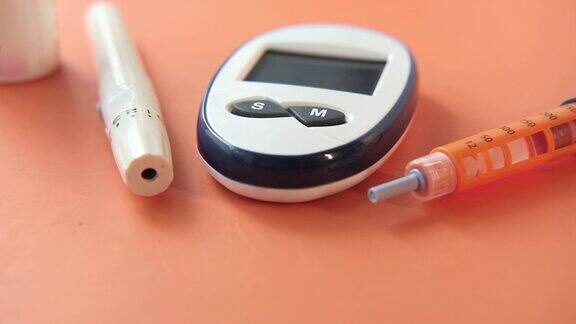 糖尿病测量工具和胰岛素笔橙色背景