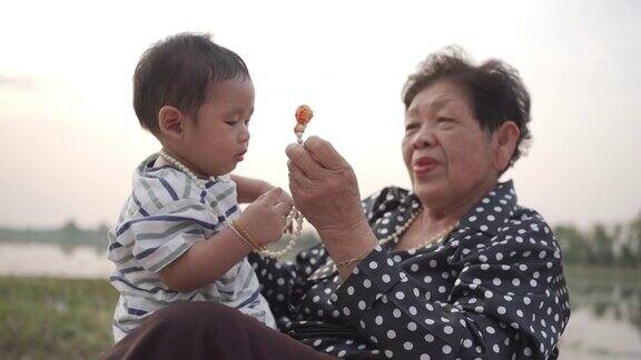 亚洲的奶奶和孙子坐在一起在公园的花园里玩幸福的亚洲家庭观念