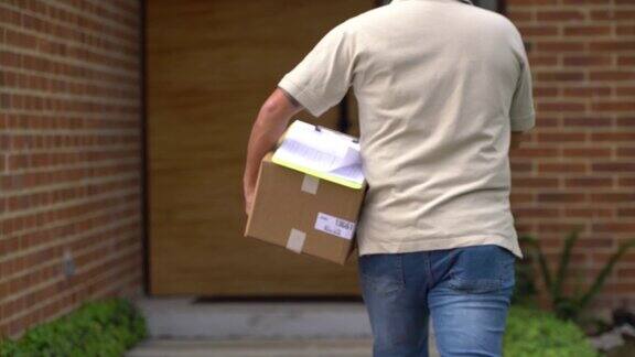 邮局工作人员看剪贴板然后敲门送包裹的背影