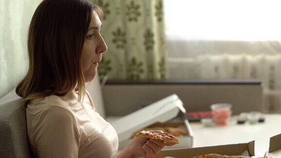 孤独悲伤的女孩拿着披萨坐在家里的沙发上看电影