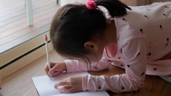 混血亚洲女孩坐在地板上在家学习写字在家学习教育