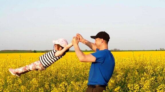 一个男人变成了一个孩子快乐的父亲和女儿在大自然中乡下的家庭一个男人带着孩子在油菜花地里