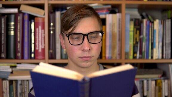 一个年轻人正在图书馆看书一个戴眼镜的人仔细地看这本书的特写背景是书架上的书图书馆的书