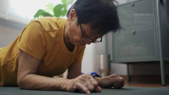 亚洲老年妇女在Covid-19隔离期间跟随在线教程和在家锻炼