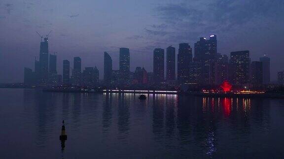 黄昏时分照明青岛市区著名的海湾纪念碑航拍全景4k中国