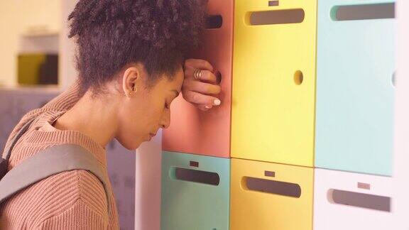 心烦意乱的年轻混血学生靠在储物柜上在校园里欺负人