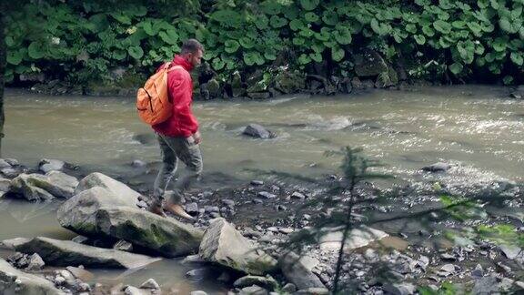 年轻的大胡子男子沿着山河徒步旅行