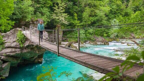 一个女人正穿过山溪上的木吊桥