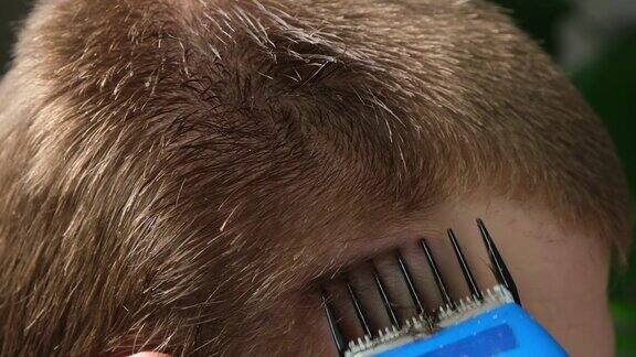 一个男人正在家里用电动剪子理发家里的发型省下理发师的钱