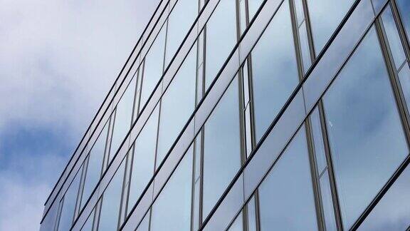 蓝色的夏日天空云朵反射在办公大楼的玻璃幕墙上