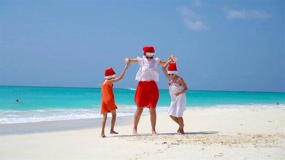 小女孩和年轻的母亲在海滩圣诞假期圣诞帽