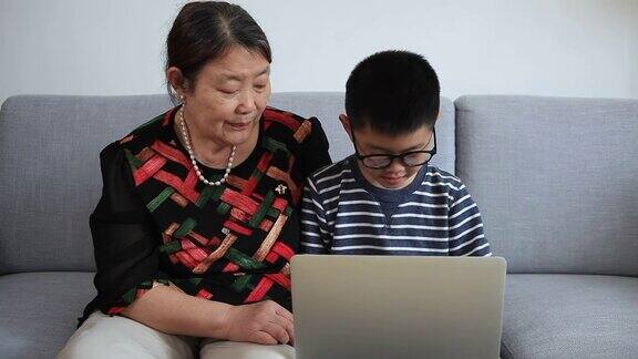 奶奶称赞孙子在室内使用笔记本电脑