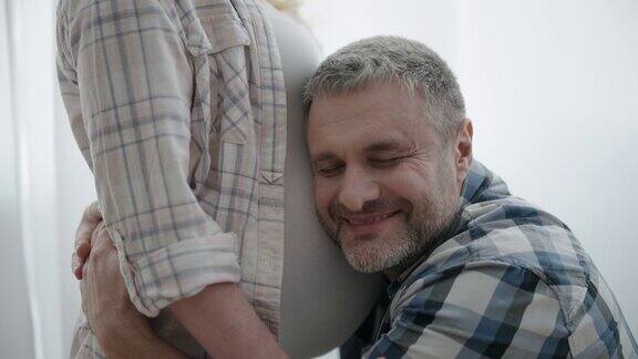 兴奋的男人拥抱怀孕的妻子亲吻肚子产前与婴儿的亲密关系