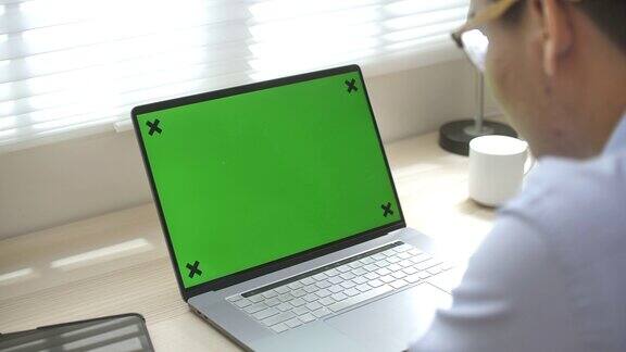 在家里用绿屏幕笔记本电脑的人