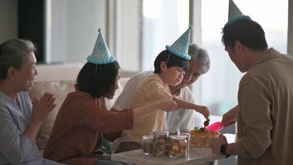 亚洲华人多代家庭庆祝生日用菜刀切生日蛋糕