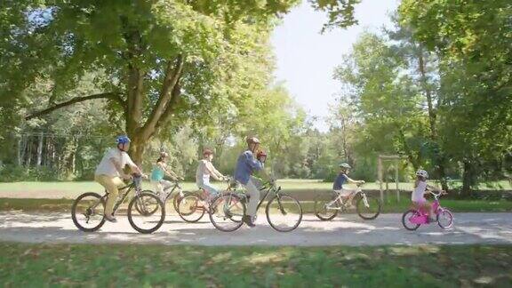 孩子们骑着自行车穿过公园他们的父母和祖父母