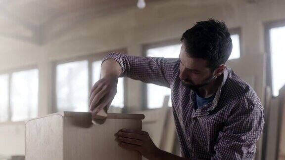 一名木匠用砂纸在家具上做最后的加工