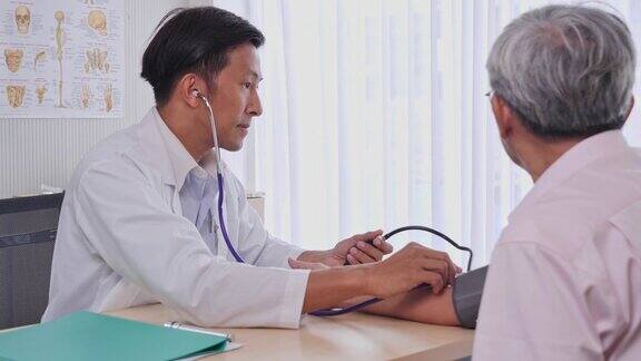 亚洲男性医生在医院的检查室为资深患者测量血压资深亚洲男性由医疗专业人员进行健康检查