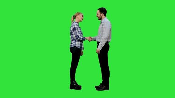 两个年轻人在不经意间握手看着镜头大拇指向上翘在绿屏上色度键