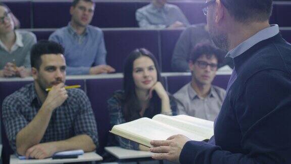 一位大学教授正在给一个多民族学生上课他手里拿着一本书