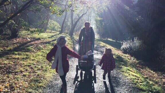 活跃的家庭散步在冬季公园在明亮的阳光和寒冷的日子他们呼吸蒸汽