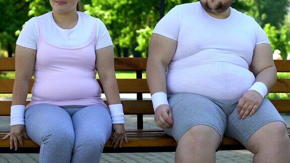 可笑的胖女人和男人坐在长椅上互相调情感慨不已