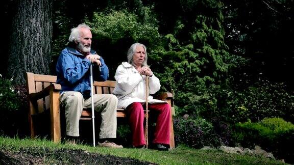 一对老年夫妇在花园长椅上聊天