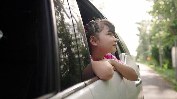 快乐的亚洲小女孩享受和家人在车在夏天的公路旅行假期