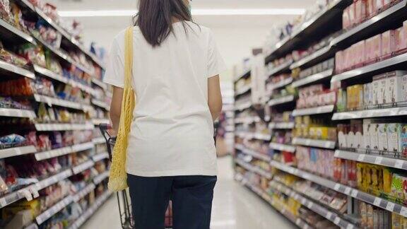亚洲年轻女子在超市使用可重复使用的袋子购物
