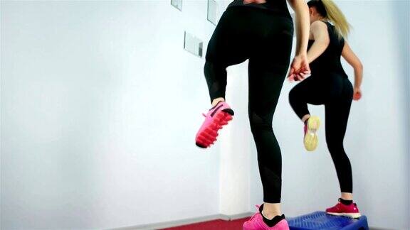 健美操女孩脚慢动作在健身房里踏板子上做运动健美操课上的年轻女性健美操步