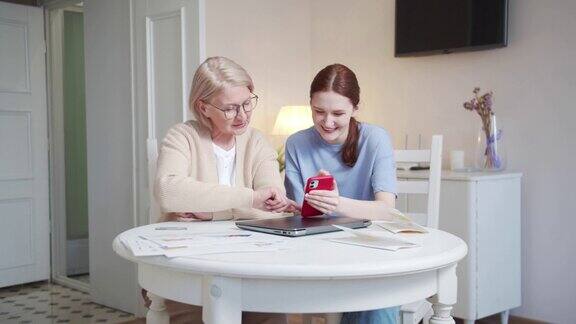 一位老妇人和她的孙女一起浏览着他们手机上的新闻动态他们又笑又笑