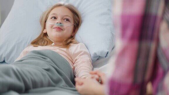 可爱的小女孩躺在病床上牵着妈妈的手