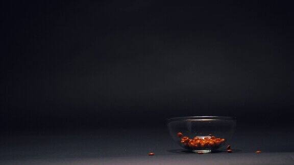 橙色糖果在玻璃碗中缓慢下落复制空间在黑色黑板纹理背景上