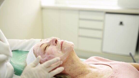 美容师在老年病人脸上按摩去角质霜