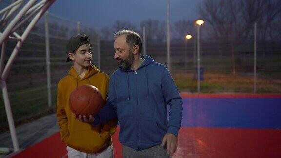 父亲和儿子一起在户外篮球场上玩耍