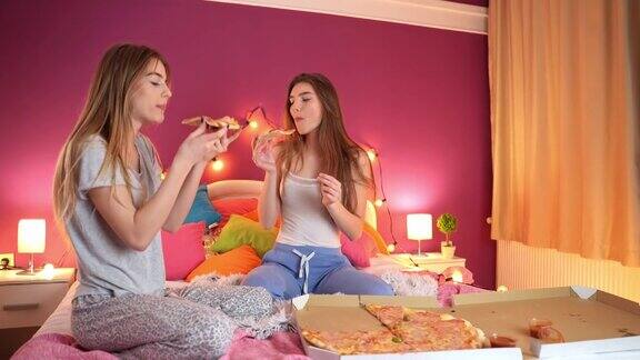 十几岁的女孩在过夜时在床上吃披萨