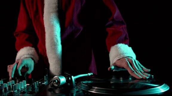 圣诞派对DJ在转盘上刮黑胶唱片音乐节目主持人穿着传统的红色圣诞老人服装播放音乐