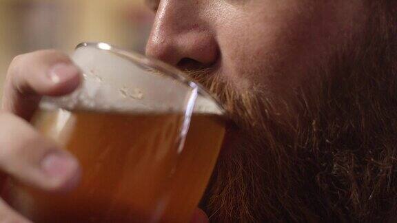 一个年轻的红胡子白人男子在喝啤酒