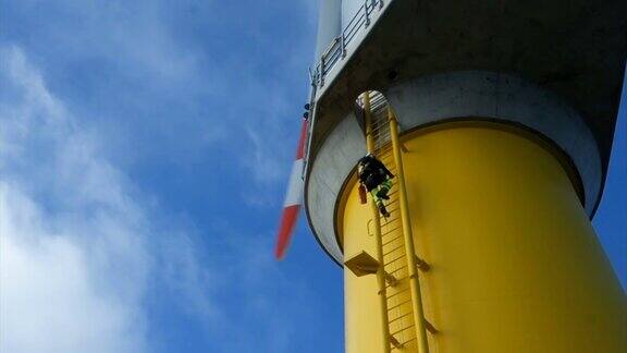 绳索进出技术员(手工高工工业攀登者)爬上最大的风力涡轮机上的梯子戏剧性的天空和身