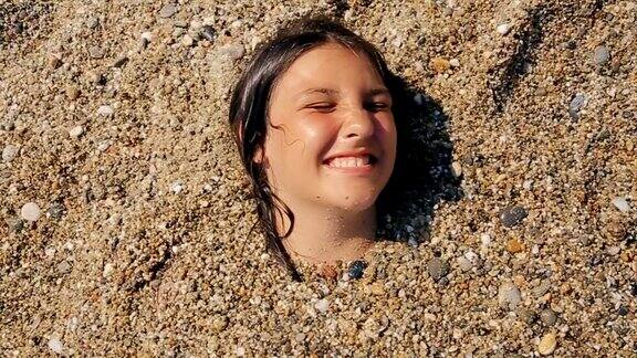 沙滩上躺在沙子里的有趣少女