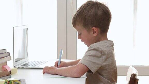 在新冠肺炎疫情隔离期间小学生在电脑上做作业自我孤立7岁的儿子在家里用笔记本电脑在线学习