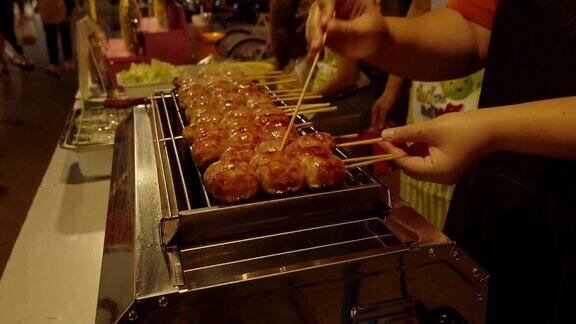 游客走在泰国夜市购买食物服装在周末假期厨师正在烤香肠