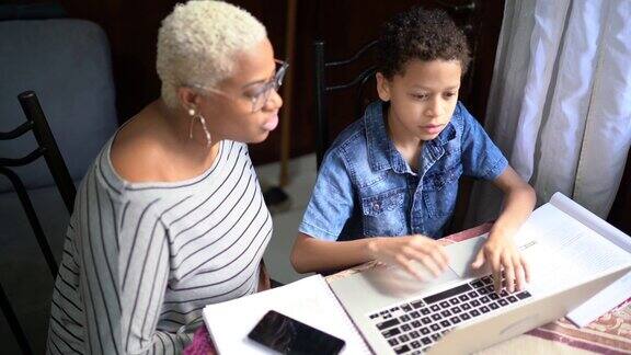 母亲和儿子在家里用笔记本电脑在线学习