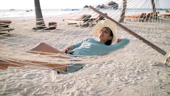 一个女人躺在沙滩上的吊床上放松