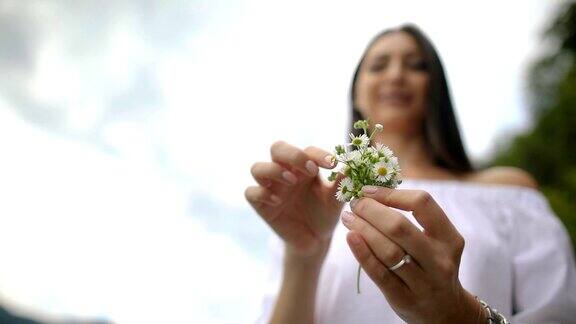 一个女人捡起雏菊从花上摘下花瓣