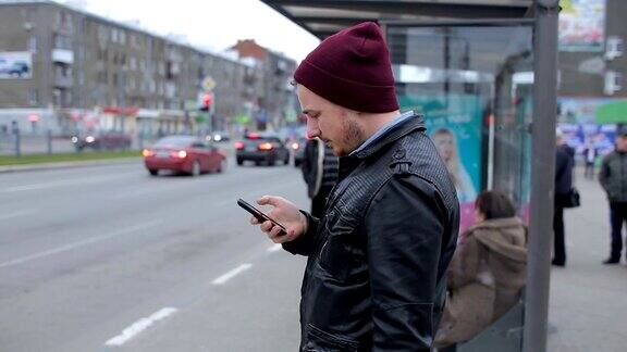帅哥在公交车站等车时看手机