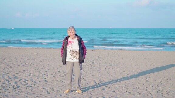 日落时分一位老妇人站在海滩上迎着海浪