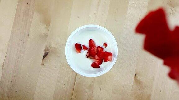 健康的草莓落在白色的酸奶上