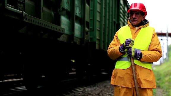 戴着红色安全帽的铁路工人站在铁轨旁看着货车