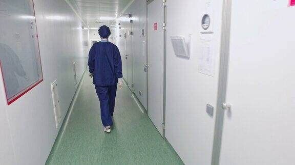 身着防护服的女医生走在医院走廊上的背影